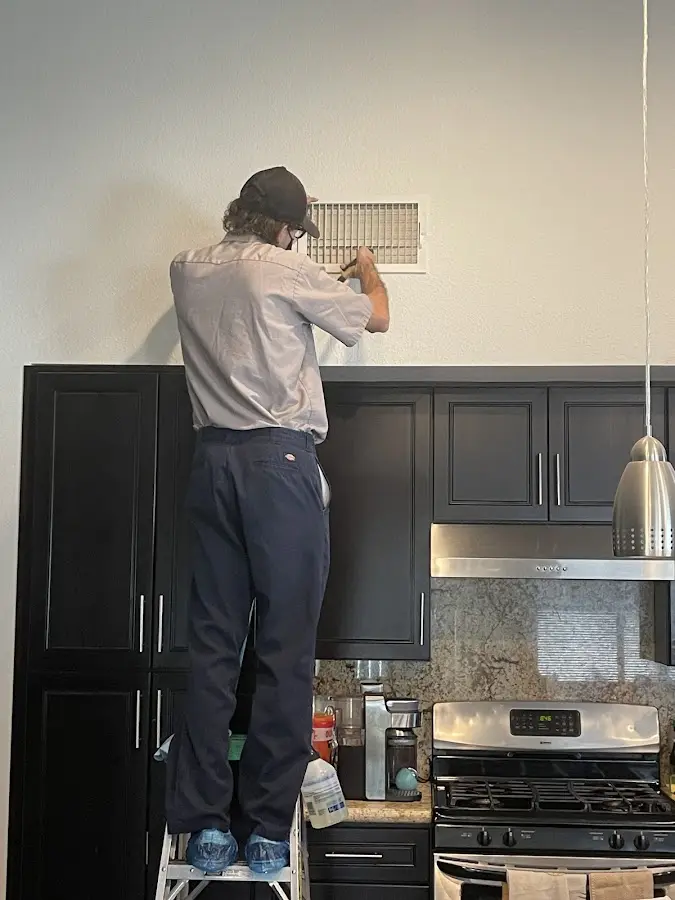 Technician inspecting an air vent during HVAC service in Urban Honolulu